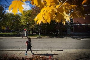 Student walking across campus on a fall day.